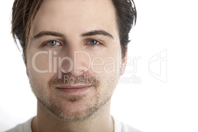 Attractive man in front of a white background looks straight int