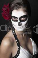 Woman with makeup of la Santa Muerte with red roses in front of