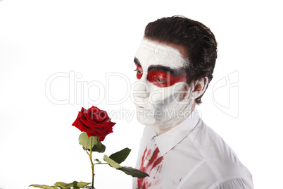 Man with white mascara and bloody shirt holds red rose
