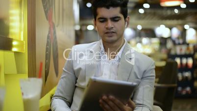 Businessman sitting in a café and talking on a digital tablet