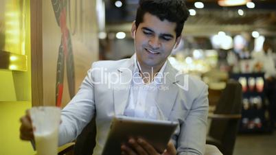 Businessman sitting in a café and listening music on a digital tablet
