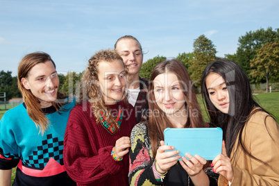 Adults young people look at the park on tablet computer