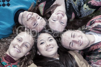 Group of young people lying head to head in the park