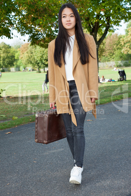 Young woman with suitcase running down the street