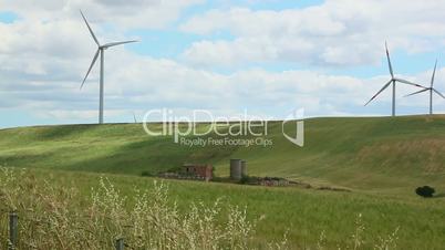 Pan shot of spinning wind turbines on a hill