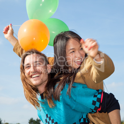 Man carrying young woman with balloons