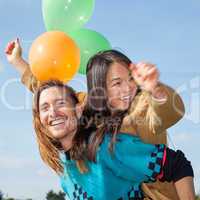 Man carrying young woman with balloons