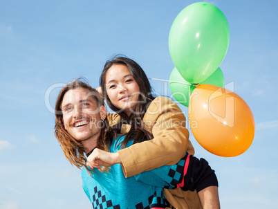 Man carrying young woman with balloons