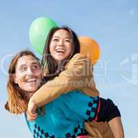 Man carrying young woman with balloons