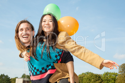 Man carrying young woman with balloons