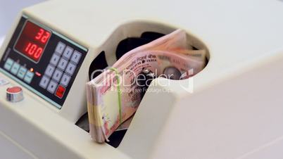 Locked-on shot of Indian currency notes being counted in a machine