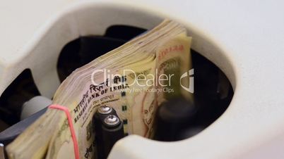 Locked-on shot of Indian currency notes being counted in a machine