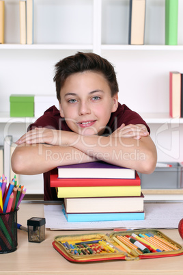 Junger Schüler auf einem Stapel Bücher in der Schule