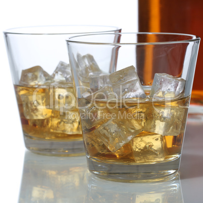 Whisky oder Whiskey im Glas und Flasche mit Eiswürfel