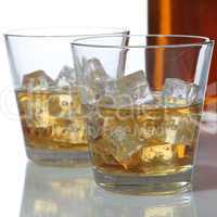 Whisky oder Whiskey im Glas und Flasche mit Eiswürfel