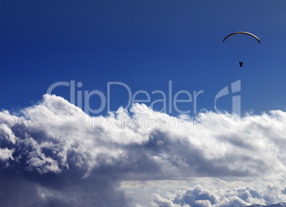 Silhouette of paraglider and blue sunny sky