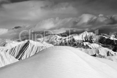 Black and white  off-piste snowy slope and cloudy mountains