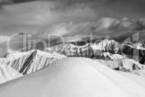 Black and white  off-piste snowy slope and cloudy mountains