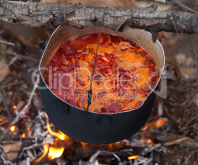 Cooking borscht (Ukrainian traditional soup) on campfire