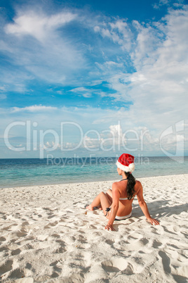 Woman in santa hat on the beach