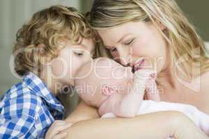 Young Mother Holds Newborn Baby Girl as Brother Looks On
