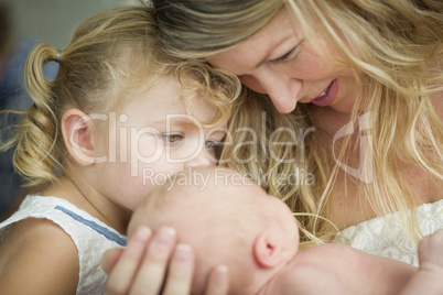 Young Mother Holds Newborn Baby Girl as Young Sister Looks