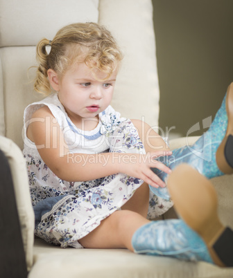 Blonde Haired Blue Eyed Little Girl Putting on Cowboy Boots