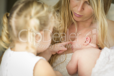 Young Mother Holds Newborn Baby Girl as Young Sister Looks