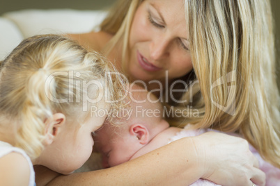 Young Mother Holds Newborn Baby Girl with Young Sister