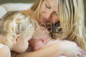 Young Mother Holds Newborn Baby Girl with Young Sister