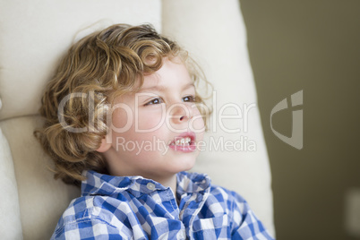 Cute Blonde Boy Daydreaming and Sitting in Chair