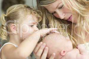 Young Mother Holds Newborn Baby Girl as Young Sister Looks