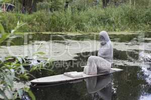 Stone sculpture of a priest on the water