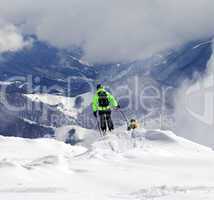 Freeriders on off-piste slope and mountains in haze