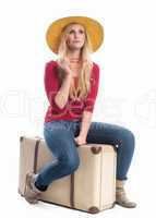 Frau sitzt auf Koffer und wartet