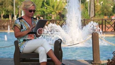 woman using digital tablet near the park fountain