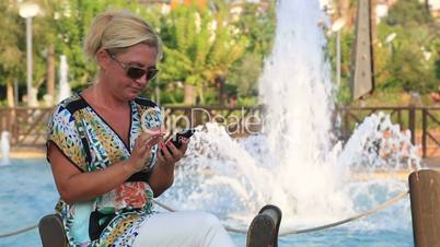 woman using smart phone near the park fountain