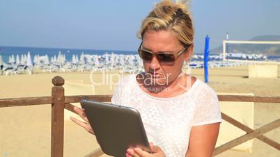 woman with tablet computer on the beach