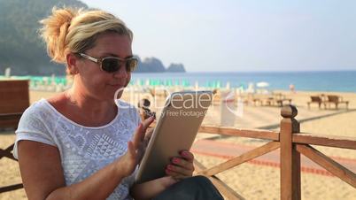 woman with tablet computer on the beach