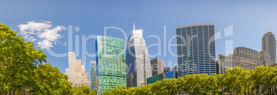 Modern skyscrapers surrounded by park trees under a beautiful bl