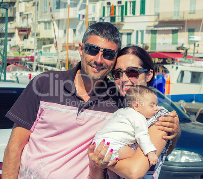 Happy couple on holidays embracing sleeping son