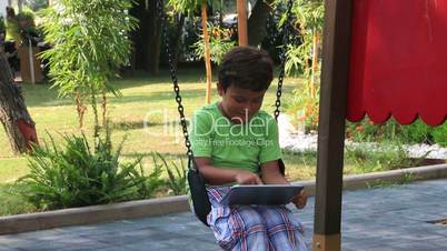 child swinging and using digital tablet