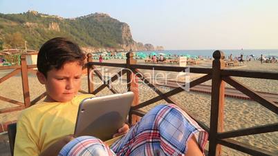 child with digital tablet on the beach