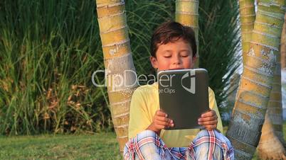 Cute kid using digital tablet at the park
