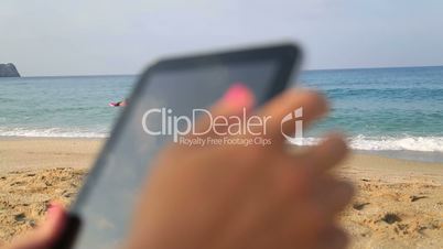 woman hands holding digital tablet on the beach