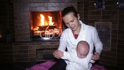 mother sitting with her baby near the fireplace at Christmas