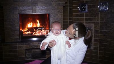 mother sitting with her baby near the fireplace at Christmas