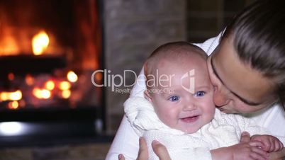mother sitting with her baby near the fireplace at Christmas