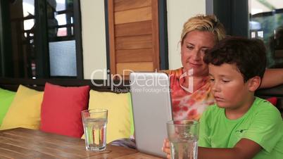 Mother and son with digital tablet at cafe