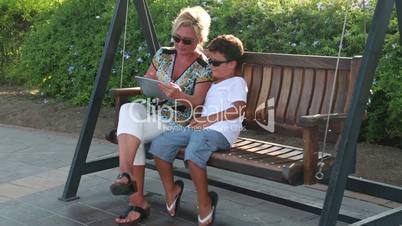 mother and son swinging and using digital tablet